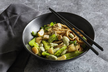 Bowl of vegan miso udon bowl with tofu, snap peas, broad beans and turnips - EVGF04418
