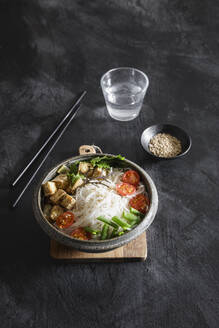 Bowl of vegan Tom kha kai soup with tofu, tomatoes, salad, rice noodles, sesame seeds and scallion - EVGF04419
