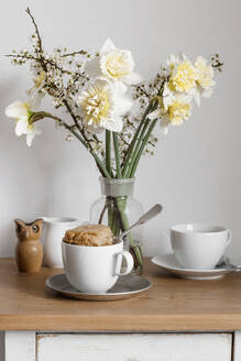 Kuchen im Becher und weiß blühende Blumen auf dem Nachttisch - EVGF04425