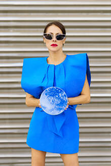 Frau in blauem Kleid und mit Spiegel vor einem Fensterladen - JSMF02925