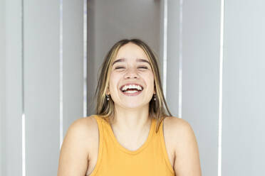 Cheerful woman with eyes closed laughing at home - DSIF00737