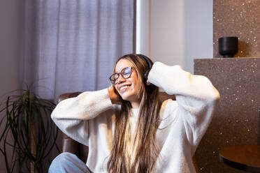 Smiling woman wearing eyeglasses enjoying music at home - DSIF00746