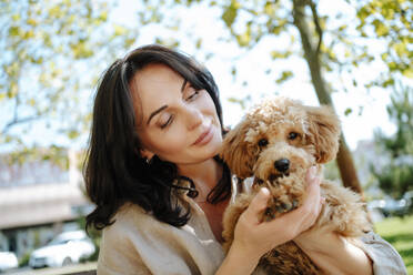 Liebevolle Frau hält Pudelhund im Park - MDOF01691