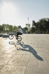 Man riding BMX bike in park on sunny day - MRPF00024