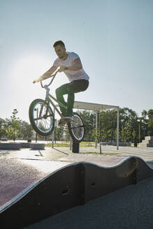 Mann macht Stunt mit BMX-Rad auf Sportstrecke im Park - MRPF00026