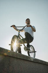 Man riding BMX bike on wall under sky - MRPF00029
