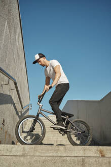 Mann fährt BMX-Rad auf Treppe unter Himmel - MRPF00034