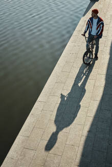 Mann steht mit BMX-Rad in der Nähe des Sees an der Uferböschung - MRPF00043