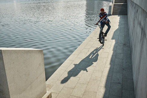 Mann macht Stunt mit BMX-Rad in der Nähe des Sees an der Uferböschung - MRPF00046