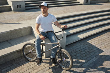 Nachdenklicher Mann sitzt mit BMX-Rad in der Nähe von Stufen - MRPF00048