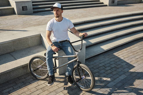 Nachdenklicher Mann sitzt mit BMX-Rad in der Nähe von Stufen - MRPF00048