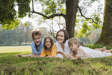 Eltern liegen mit Sohn und Tochter auf dem Rasen im Park - NDEF01440