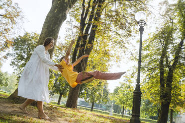 Mutter schaukelt Tochter im Park - NDEF01455