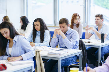 Multi-ethnic students studying at desk in classroom - NJAF00641