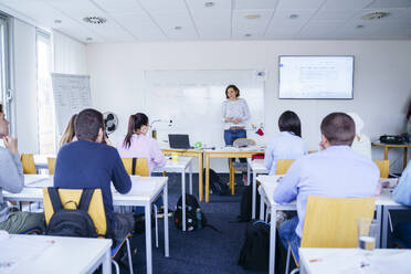 Woman teaching to multi-ethnic students in classroom - NJAF00653