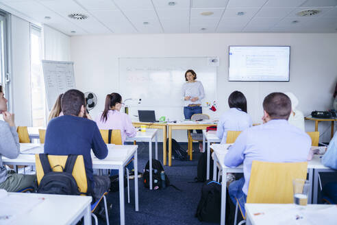 Frau unterrichtet multiethnische Schüler im Klassenzimmer - NJAF00653