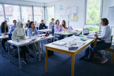 Smiling teacher teaching to multi-ethnic students in classroom - NJAF00656