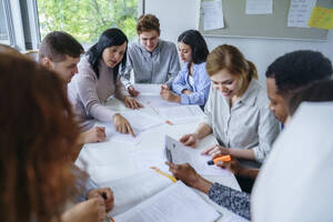 Multiethnische Schüler lernen gemeinsam am Schreibtisch in einer Schulklasse - NJAF00668