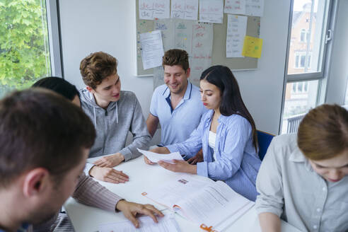 Multiethnische Schüler diskutieren und lernen am Schreibtisch im Klassenzimmer - NJAF00669