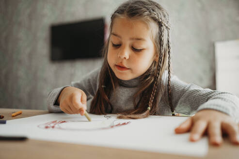 Mädchen mit geflochtenen Haaren zeichnet mit Buntstift zu Hause - ANAF02401