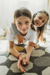 Lächelnde Schwestern haben Spaß auf dem Teppich zu Hause - ANAF02405