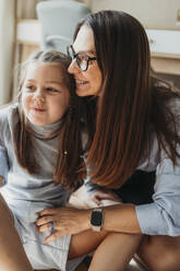 Liebevolle Mutter sitzt mit ihrer Tochter zu Hause - ANAF02410