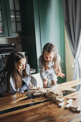 Überrascht Mutter und Tochter Blick auf gefallenen Blöcke auf dem Tisch in der Küche - ANAF02439