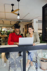 Lächelnde Geschäftskollegen bei der Arbeit am Laptop im Café - JOSEF22130