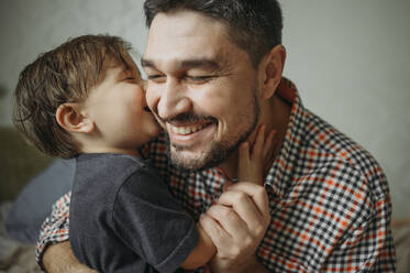 Glücklicher Vater umarmt süßen Sohn zu Hause - ANAF02448