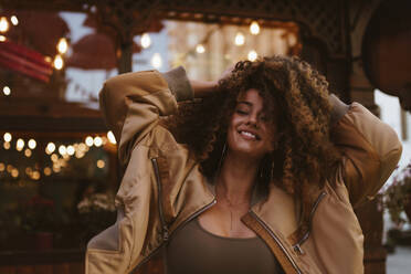 Smiling woman with hands in hair at sunset - ANNF00631