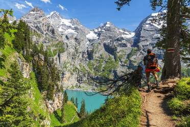 Rear view of a hiker standing on the trail in the wood surrounding Oeschinensee lake, Oeschinensee, Kandersteg, Bern Canton, Switzerland, Europe - RHPLF29068