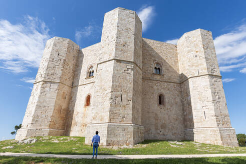 Man admires the octagonal castle of Castel del Monte in a clear sunny day, UNESCO World Heritage Site, Apulia, South of Italy, Italy, Europe - RHPLF29071