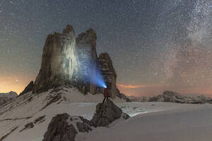 Hiker with head torch views the Tre Cime di Lavaredo on a starry night with the Milky Way, winter view, Tre Cime di Lavaredo (Lavaredo peaks), Sesto (Sexten), Dolomites, South Tyrol, Italy, Europe - RHPLF29082