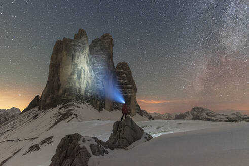 Hiker with head torch views the Tre Cime di Lavaredo on a starry night with the Milky Way, winter view, Tre Cime di Lavaredo (Lavaredo peaks), Sesto (Sexten), Dolomites, South Tyrol, Italy, Europe - RHPLF29082