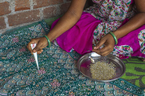 Adivasi woman sticking beads onto a sari in a village in Narmada district, Gujarat, India, Asia - RHPLF29174