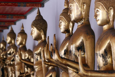 Row of golden Buddha statues meditation Wat Pho Temple of the