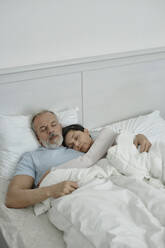 Wife cuddling her husband while sleeping together in bed - KPEF00341