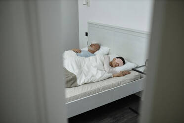 Ehemann und Ehefrau schlafen im Bett in einem pastellfarbenen Zimmer - KPEF00342