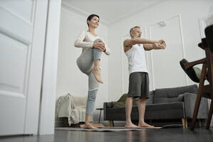 Couple doing stretching exercises in morning at home - KPEF00354