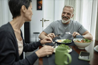 Positive husband talking to his wife during lunch at home - KPEF00370