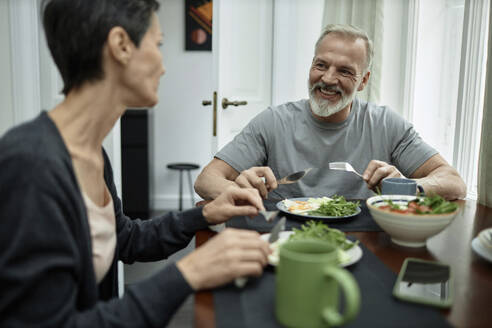 Positiver Ehemann im Gespräch mit seiner Frau beim Mittagessen zu Hause - KPEF00370