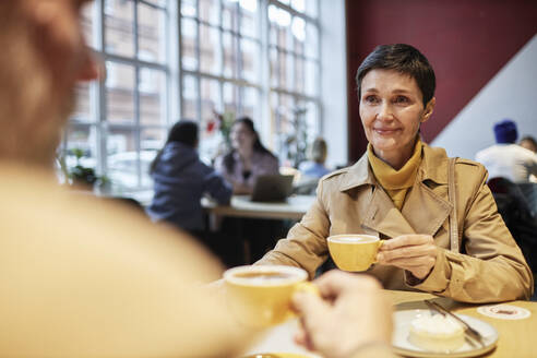 Frau schaut ihren Mann an, während sie im Café nach einem Spaziergang Kaffee trinkt - KPEF00397