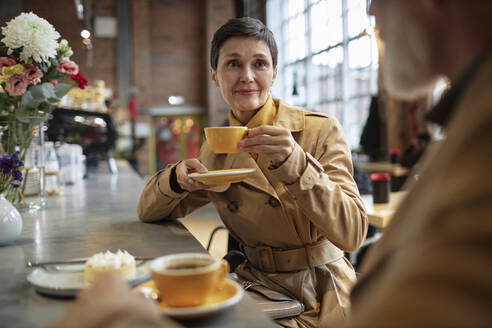 Loving wife enjoying hot drink while sitting in cafe after walk with her husband - KPEF00398