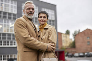 Porträt eines älteren Paares, das sich bei einem Spaziergang in der Stadt umarmt - KPEF00399