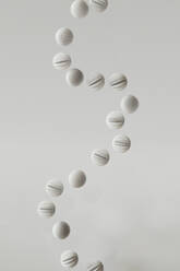 3D render of row of striped spheres floating against white background - GCAF00489