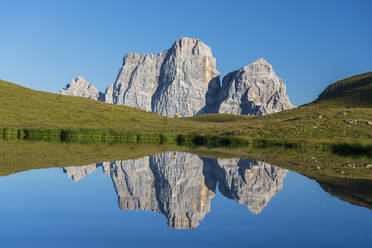 Hiker and Mount Pelmo reflected in the water of Baste Lake on a sunny day, Belluno Dolomites, Belluno province, Veneto, Italy, Europe - RHPLF29396