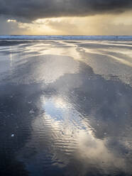 Rain clouds and reflections on Rhossili beach at sunset showing the shipwreck of the Helvetia, Rhossili, Gower, South Wales, United Kingdom, Europe - RHPLF29782