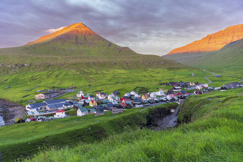 Colorful houses of the village of Gjogv with the mounatins lit by the early sun, sunrise view, Eysturoy island, Faroe islands, Denmark, Europe - RHPLF29852