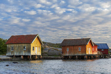 Traditional old rorbu cabins overlooking the ocean at sunset, Norway, Scandinavia, Europe - RHPLF29857