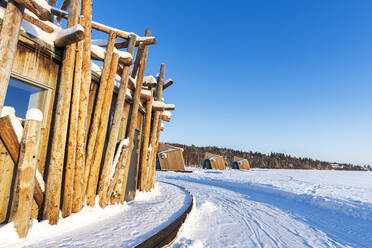 Architectural structure of Arctic Bath hotel made of logs on frozen Lule River with cutting-edge chalets in the background, Harads, Norrbotten, Swedish Lapland, Sweden, Scandinavia, Europe - RHPLF29867